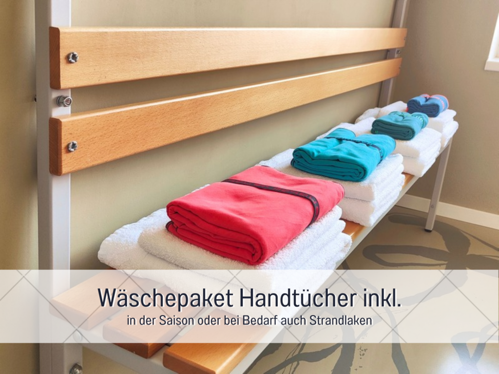 Gestapelte Handtücher in verschiedenen Farben auf einer Holzbank im Badezimmer.